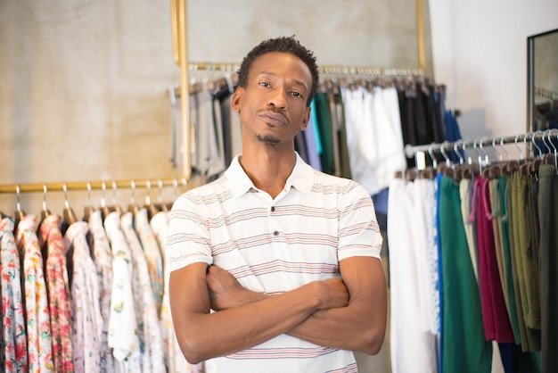 Ritratto di uomo afroamericano dopo aver fatto la scelta in negozio. un giovane serio ha scelto nuovi vestiti e scarpe da acquistare in un negozio di abbigliamento avendo tempo libero e posando per la macchina fotografica. acquisto di vestiti maschili concetto