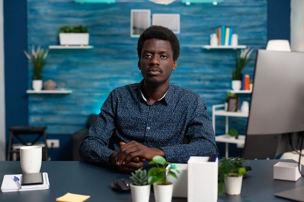 Portrait of african american man looking into camera at desk young black man sitting in cozy modern ...