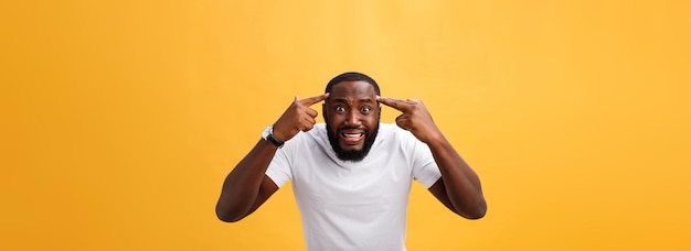 Portrait of african american man with hands raised in shock and disbelief isolated over yellow backg