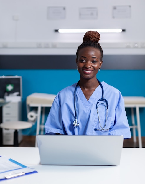 Free photo portrait of african american nurse using laptop at white desk