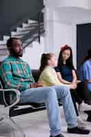 Free photo portrait of african american patient looking tired waiting in busy hospital reception room with diverse people. bored man sitting down looking pensive waiting for receptionist to call his name.