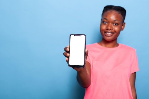 手に白い空の画面でスマートフォンを保持しているアフリカ系アメリカ人のティーンエイジャーの肖像画