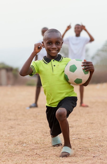 Foto gratuita ritratto di bambino africano con pallone da calcio