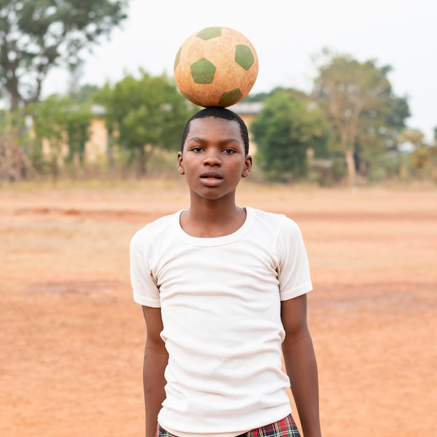 Foto gratuita ritratto di bambino africano con pallone da calcio