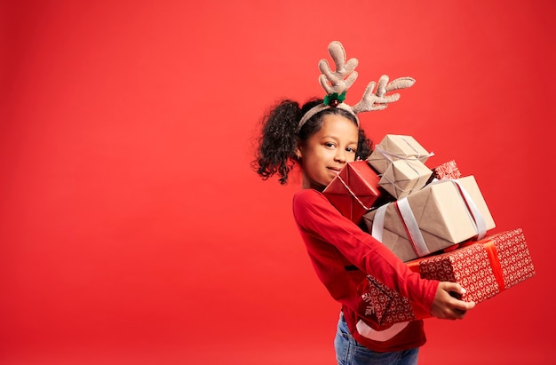 Portrait of African girl carrying stack of Christmas gifts