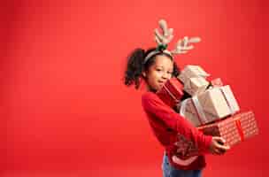 Free photo portrait of african girl carrying stack of christmas gifts