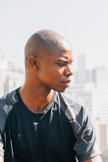 Free photo portrait of a african shaved young man looking over shoulder