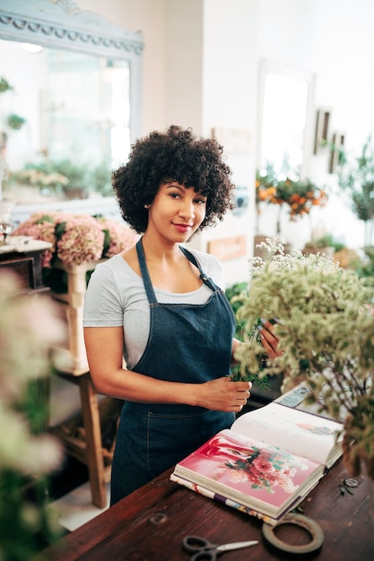 Portrait of an african woman with flower photo album on desk in shop