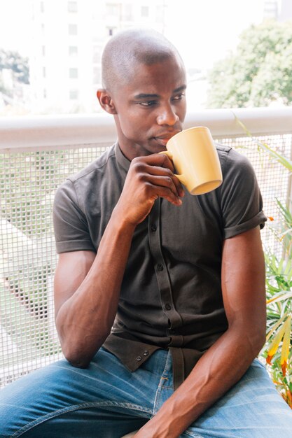 Portrait of an african young man drinking the coffee in the balcony