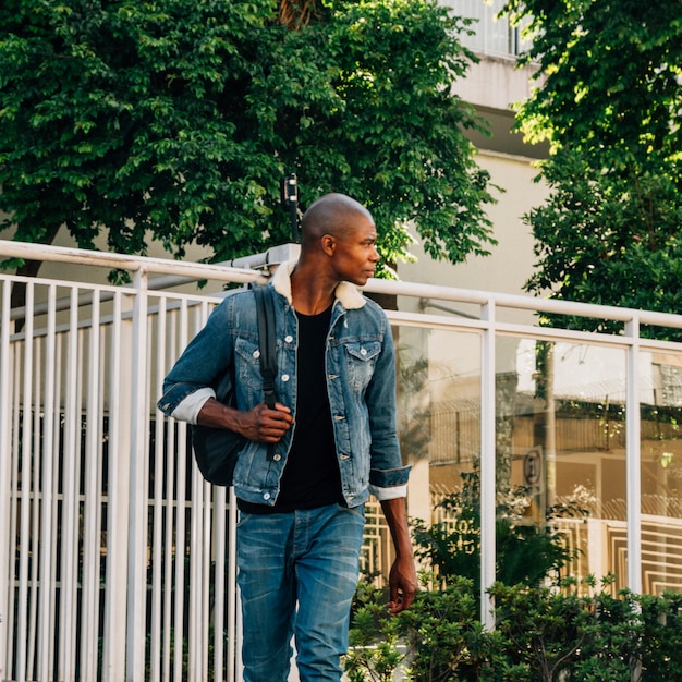 Portrait of a african young man with his backpack on shoulder looking away