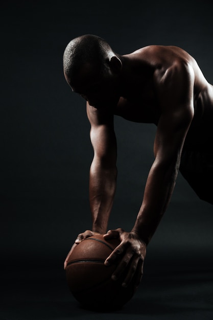 Портрет афро-американского баскетболиста, делающего упражнение отжимания на шаре