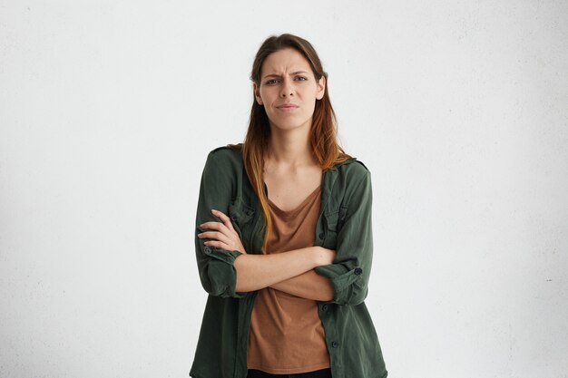 Portrait of aggravated sad woman with long face and healthy skin standing crossed hands expressing her dissatisfaction