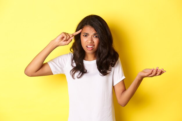 Portrait of angry and confused africanamerican girl scolding someone for being stupid pointing