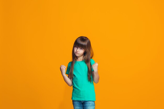 Portrait of angry teen girl on a orange studio background