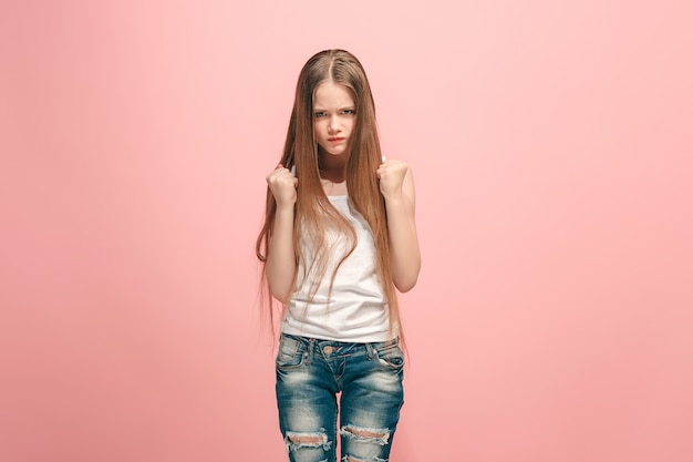 Portrait of angry teen girl on a pink  wall