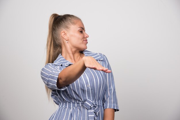 Portrait of angry woman rejecting something on gray wall.