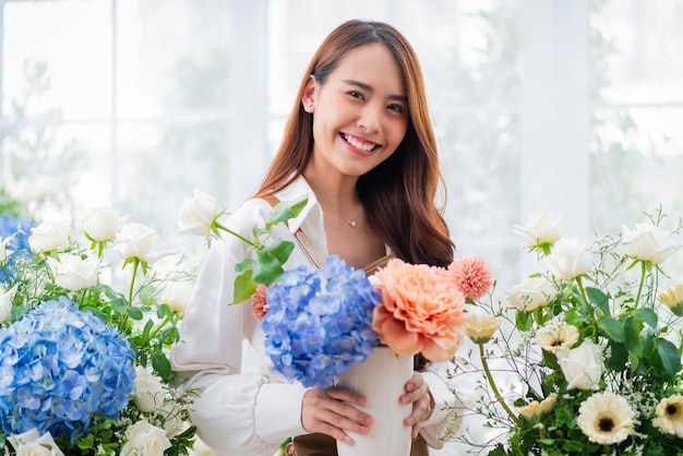 세로 아시아 여성 꽃집 미소 꽃 가게에서 꽃을 정렬 꽃 디자인 가게 행복 웃는 젊은 아가씨 가정에서 꽃 작업을 준비하는 고객을 위해 꽃병을 만드는 젊은 아가씨