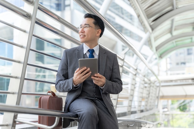Портрет азиатского делового человека делового района, старшего дальновидного руководителя с бизнес-видением телефонного компьютера в руке - концепция образа жизни деловых людей