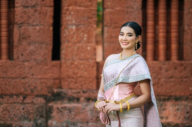 古代寺院や優雅なポーズで有名な場所でタイの美しい典型的なタイのドレスアイデンティティ文化を身に着けている肖像画アジアの魅力的な女性