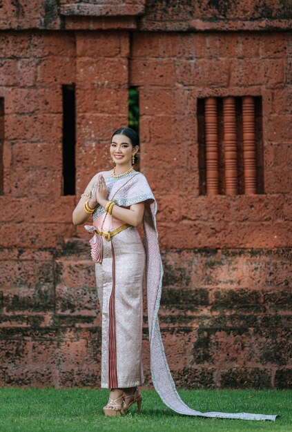 Portrait Asian charming woman wearing beautiful typical Thai dress identity culture of Thailand in ancient temple or famous place with gracefully pose