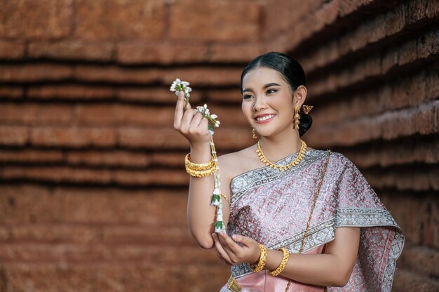 Портрет азиатской очаровательной женщины, носящей красивую типичную тайскую культуру идентичности платья Таиланда в древнем храме или известном месте