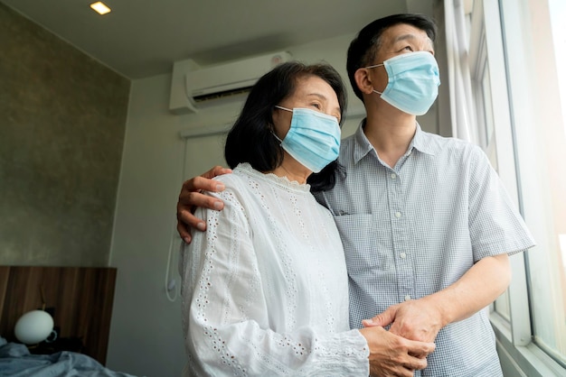 집 코비드19 발병 예방 개념에서 얼굴 의료 마스크 전염병 코로나바이러스 질병 검역소를 쓴 아시아 부부 노인 노인 남성과 여성의 초상화