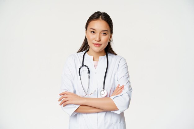 의료 유니폼을 입고 카메라를 보고 웃는 청진기를 들고 팔짱을 끼고 서 있는 아시아 의사 여성의 초상화...