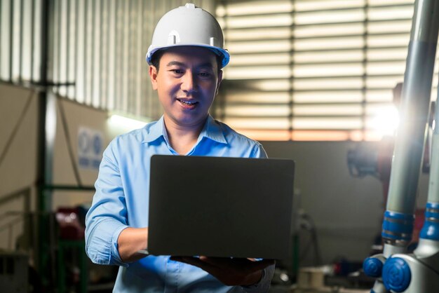 Portrait of asian emgineer male female technician in safty uniform standing and turn around to look at camera and laugh smile with cheerful and confident in machinery factory workplace background