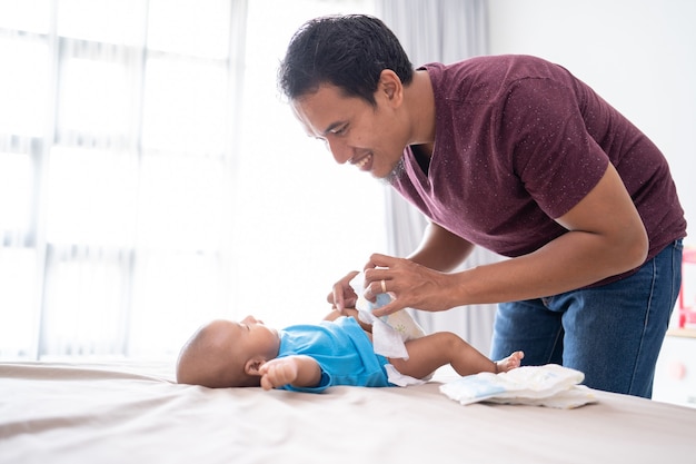 Premium Photo | Portrait of asian father changing his infant baby diaper at home