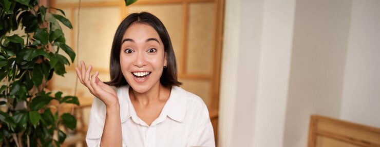 無料Photo 驚いた顔で携帯電話を持って驚いて見えるアジアの女の子の肖像画