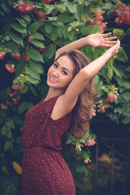 Portrait of an Asian girl posing outdoors against the flower bush