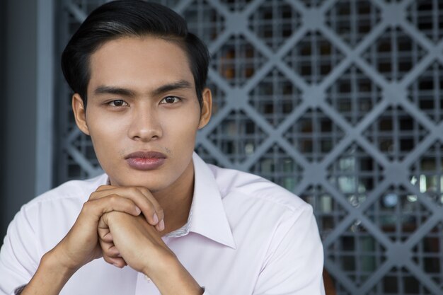 Portrait of Asian Man Holding Hands Under Chin