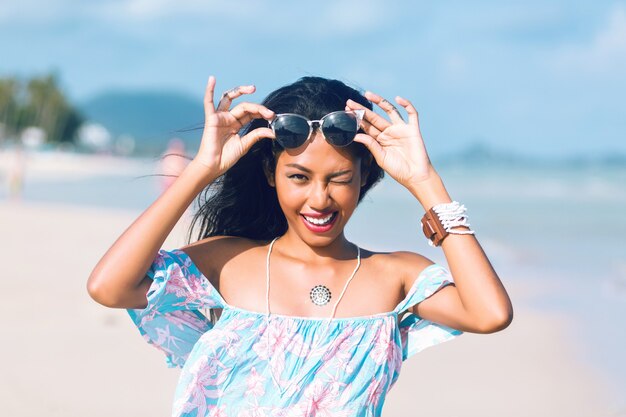 portrait of asian thai girl with sunglasses and flower dress having fun on tropical beach