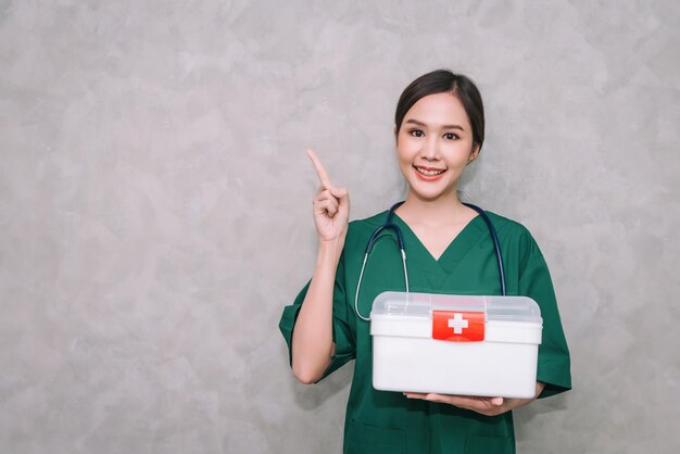 Portrait asian woman doctor wearing uniform carrying first aid box kit with copy space background