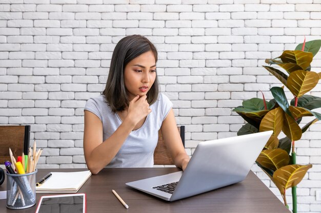Portrait of Asian woman freelancer working at home sitting at desk dining table in living room