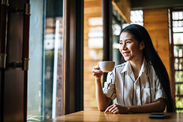 笑みを浮かべて肖像画アジア女性のコーヒーショップカフェでリラックス