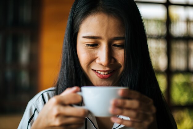 笑みを浮かべて肖像画アジア女性のコーヒーショップカフェでリラックス