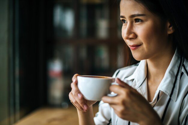 笑みを浮かべて肖像画アジア女性のコーヒーショップカフェでリラックス