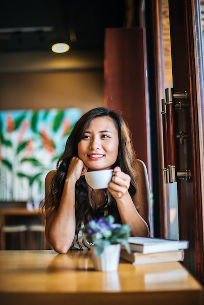 笑みを浮かべて肖像画アジア女性のコーヒーショップカフェでリラックス