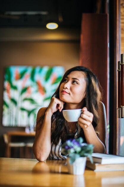 笑みを浮かべて肖像画アジア女性のコーヒーショップカフェでリラックス