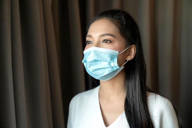 Portrait of Asian young female wear face medical mask pandemic coronavirus disease quarantine in home Covid19 outbreak prevention concept