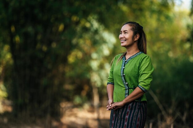 Portrait Asian young pretty woman wearing  beautiful cloths stand and smiling while relaxing in countryside thailand, copy space