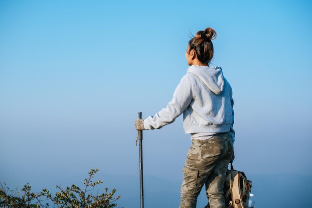 아시아 젊은 관광 여성의 초상화가 마운팅 꼭대기에서 하이킹을 하고 있으며 복사 공간이 있는 아름다운 풍경을 바라보고 있습니다. 여행 라이프스타일 방랑벽 모험 개념 휴가 야외