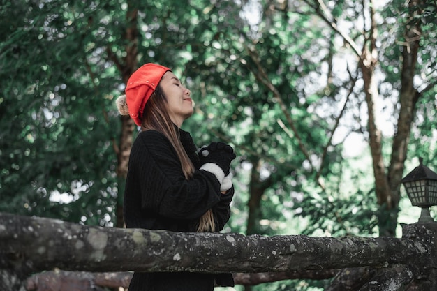 Foto gratuita ritratto di giovane donna asiatica in costume invernale che prega al mattino nel bosco il cristianesimo e la fede sperano nel concetto di amore