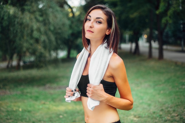 체육 여자의 초상화입니다. 도시 공원에서 조깅을 준비하는 아름 다운 젊은 스포츠 피트니스 모델.