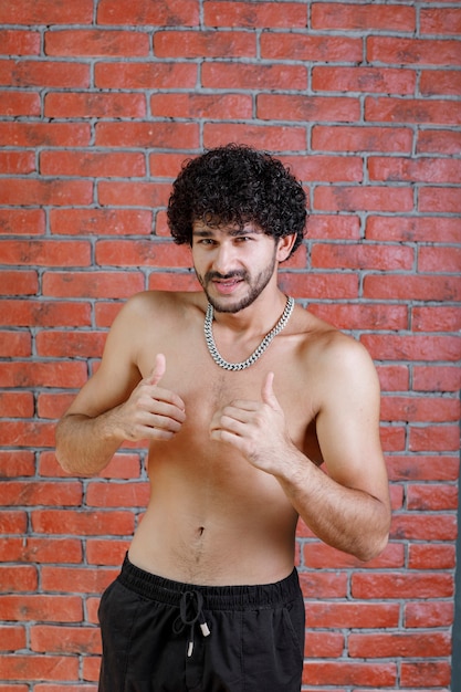 Free photo portrait of athletic half naked man giving thumbs up.