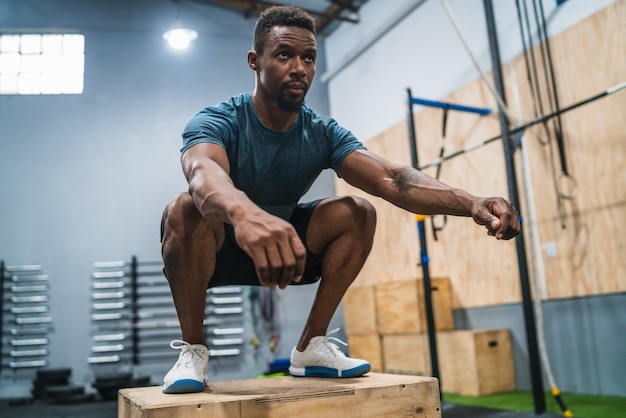 ボックスジャンプ運動を行う運動の男の肖像画。 Crossfit、スポーツ、健康的なライフスタイルのコンセプト。