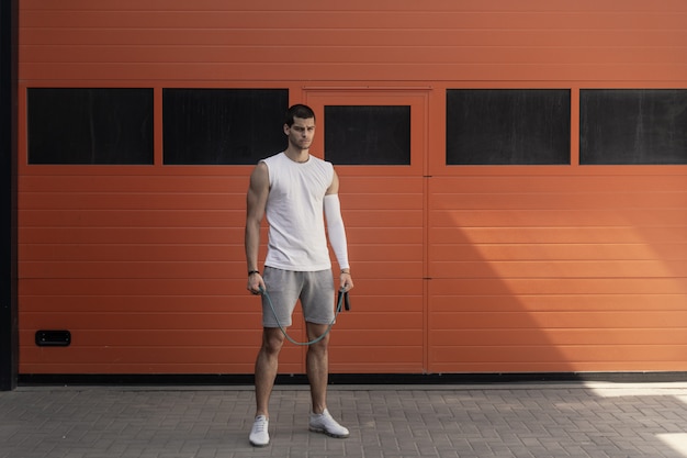 Portrait athletic, muscular man preparing for warming up with jumping rope