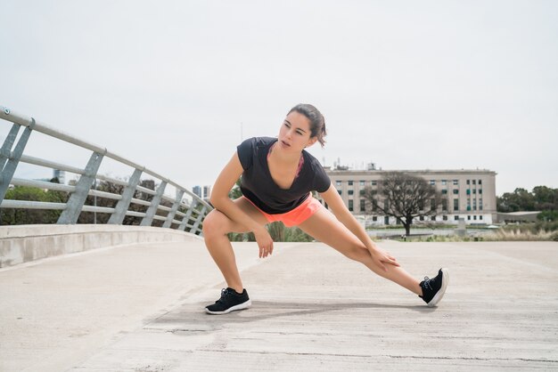 屋外で運動する前に足を伸ばしている運動女性の肖像画。スポーツと健康的なライフスタイル。