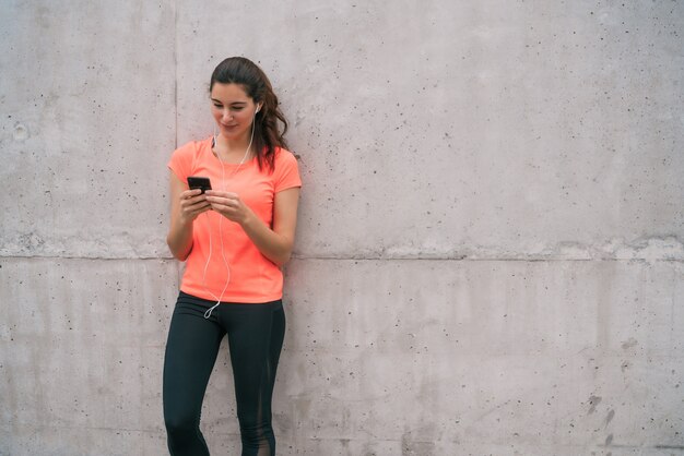 トレーニングの休憩時間に携帯電話を使用している運動女性の肖像画。スポーツと健康のライフスタイル。